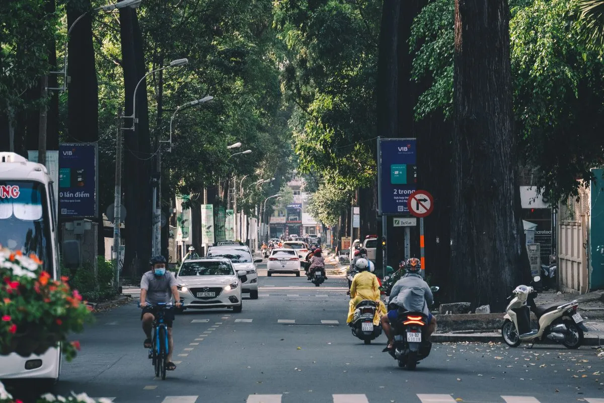 A family riding a moped in Ho Chi Minh City using a mobile phone for Grab payments